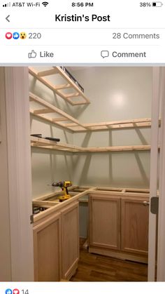 an empty kitchen with wooden shelves on the wall and wood flooring in front of it