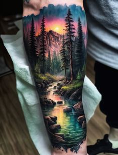 a man's arm with a painting on it and trees in the water at sunset