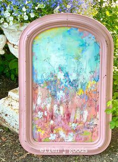 an old pink frame painted with flowers and blue sky in the background, sitting on some grass