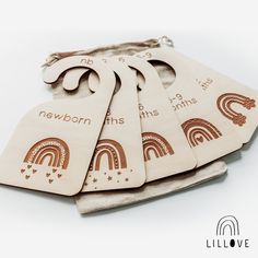 five wooden tags with rainbows and words on them are sitting in a pouch, next to each other