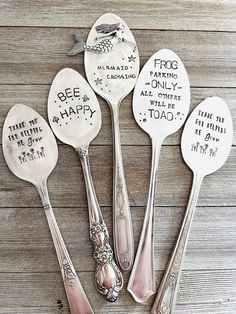 five spoons with words on them sitting next to each other in front of a wooden table