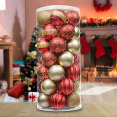 a glass container filled with red and gold christmas baubles in front of a fireplace