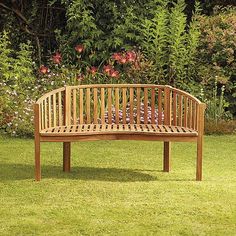 a wooden bench sitting on top of a lush green grass covered park area next to flowers