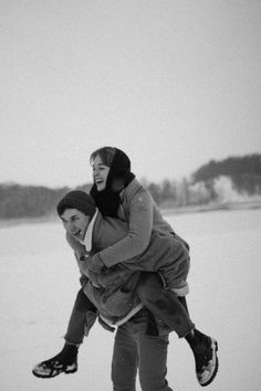 two people riding on top of each other in the snow, one person carrying another