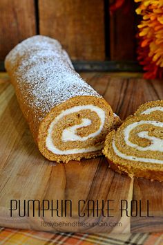 a pumpkin cake roll cut in half on a wooden cutting board with an orange flower behind it