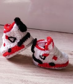 a pair of crocheted shoes sitting on top of a wooden floor next to a wall