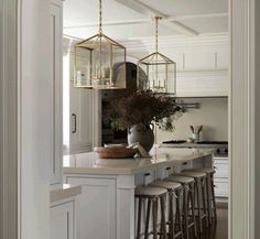 an open kitchen with white cabinets and bar stools next to the countertop area