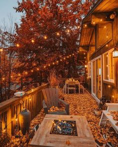 an outdoor fire pit surrounded by leaves and string lights on a deck in the fall