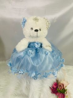 a white teddy bear wearing a blue dress