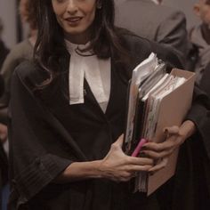 a woman in a graduation gown holding folders