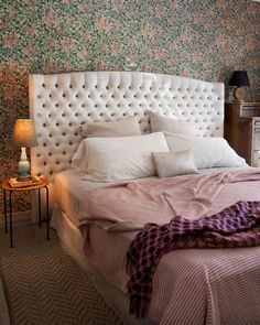 a bed with white headboard and pillows in a bedroom next to a night stand