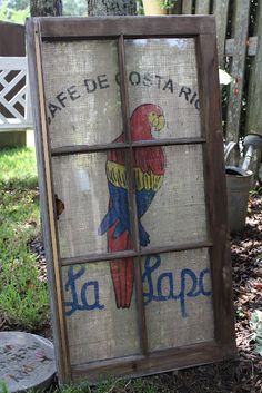 an old stained glass window with a parrot painted on it's side in the grass