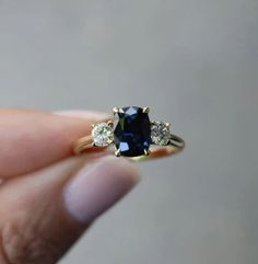 a woman's hand holding a blue and white diamond ring with three diamonds around it