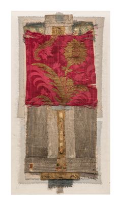 an old piece of cloth with a red and gold design on the bottom, sitting in front of a white wall