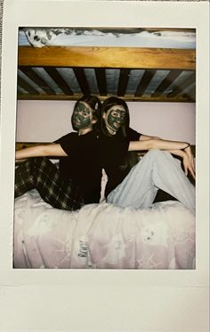 two people with painted faces sitting on a bed