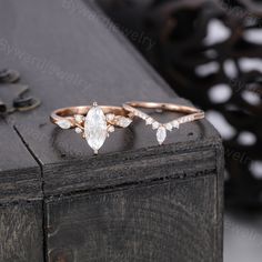 two rose gold wedding rings with pear shaped diamonds on the top and side, sitting next to each other