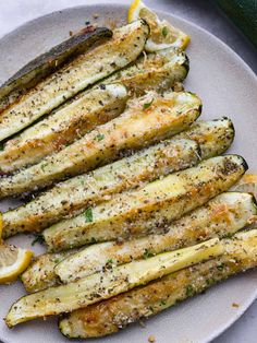 grilled zucchini on a plate with lemon wedges and parmesan cheese