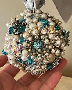 someone is holding a brooch with pearls and jewels