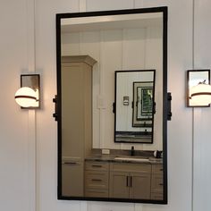 a bathroom with a large mirror on the wall and two lights in front of it