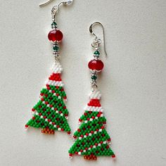 Joanne Ryngiewicz stitched these colorful beaded Christmas tree  components. Her stitching is so neat and tidy! I accented them with red lampwork beads, Swarovski 3 mm emerald crystal bicones,  sterling bead caps, lead free bead caps, teeny sterling spacers, and sterling shepherd hook ear wires. The earrings measure about 3 inches.  These are the exact earrings you will be receiving, already made and ready to ship immediately. Designed and made by me. Please convo me if you have any questions. T Beaded Christmas Tree, Diy Seed Bead Earrings, Sugar Skull Earrings, Seed Bead Patterns, Beaded Earrings Patterns, Beading Projects, Handmade Holiday, Halloween Jewelry, Earring Patterns