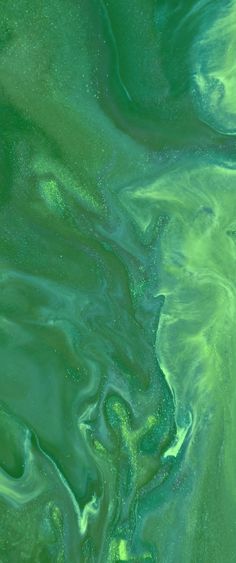 green and blue fluid paint swirls in the air, creating an interesting pattern on the surface