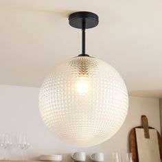 a light fixture hanging from the ceiling in a room with white walls and wooden furniture