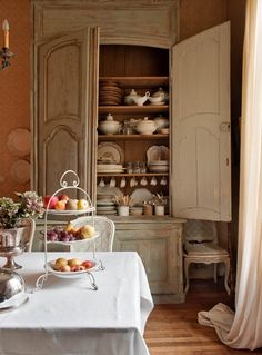 a dining room table with plates and bowls on it, next to a china cabinet