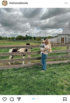 a woman standing in front of a fence next to a cow