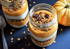 two jars filled with food sitting on top of a blue table next to pumpkins