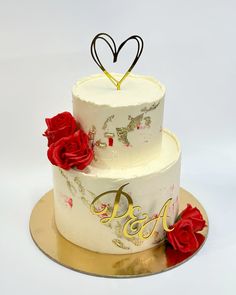 a three tiered cake with red roses on the side and a heart topper