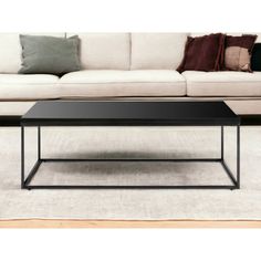 a black coffee table sitting on top of a white rug in front of a couch