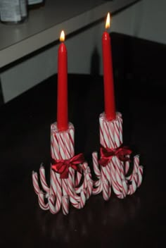 two red candles sitting on top of candy canes