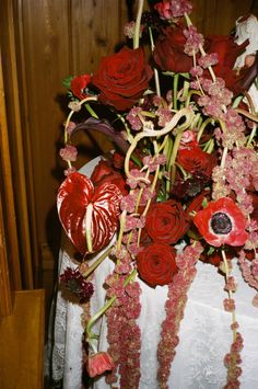 a bouquet of red flowers sitting on top of a white table cloth covered tablecloth