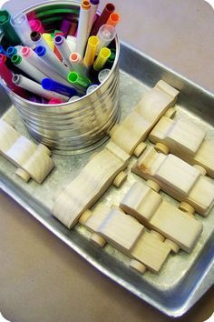 a tin filled with lots of different colored pencils next to some cut up wooden blocks