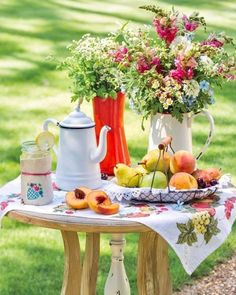 a table topped with fruit and flowers on top of a grass covered field