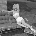 a woman laying on top of a couch next to a brick wall in a yard