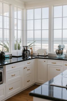 a kitchen with white cabinets, black counter tops and an ocean view from the window