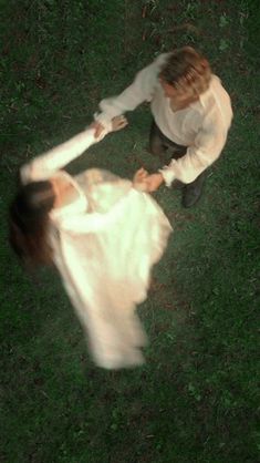 two people standing in the grass holding hands