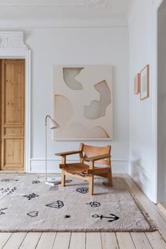 an empty room with a chair, rug and painting on the wall