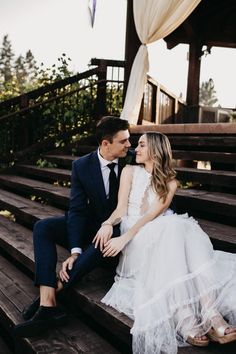 a bride and groom sitting on some steps