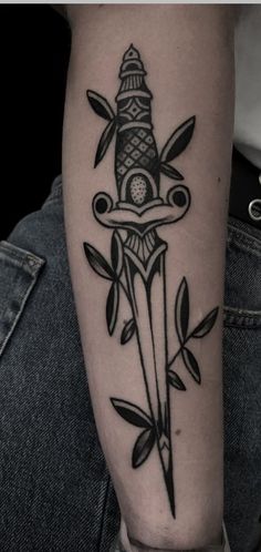 a black and white tattoo on the arm of a person with a knife in it