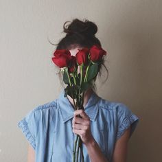 a woman holding roses in front of her face