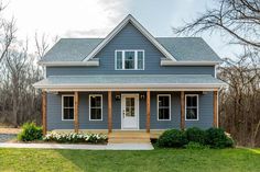 a blue house with white doors and windows in the front yard on a sunny day