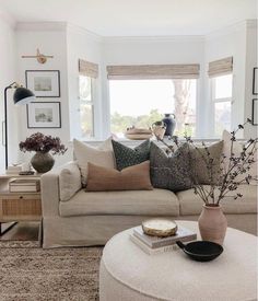 a living room filled with lots of furniture next to a large white couch and window