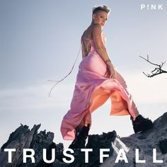 a woman in a pink dress standing on top of a rock formation with the words trust fall below her