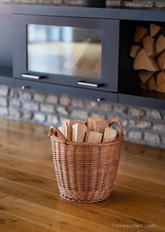 a basket filled with wood sitting on top of a wooden floor next to a tv