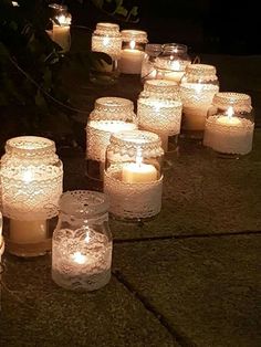 many lit candles are lined up on the ground