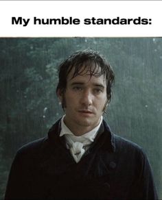 a man standing in the rain wearing a black coat and white shirt with words on it that say, my humble standards