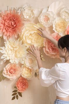 a woman standing in front of a wall with paper flowers on it's sides