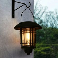 a light that is on the side of a building with trees in the back ground